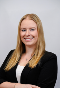 Porträtfoto einer Frau mit langen blonden Haaren im schwarzen Blazer.
